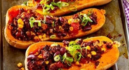 Chili con Carne serviert in einem Kürbis auf einem Holzbrett