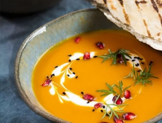 Schüssel mit köstlicher Kürbiscremesuppe, garniert mit Kürbiskernen und Sahne.