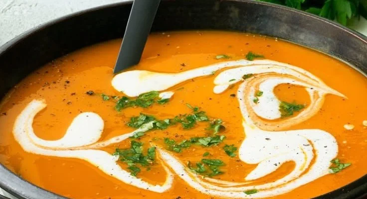 Klassische Kürbissuppe in einer Schüssel mit frischen Kräutern garniert