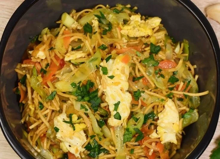 Vegetarische Bratnudeln mit Spitzkohl und Möhren auf einem Teller serviert