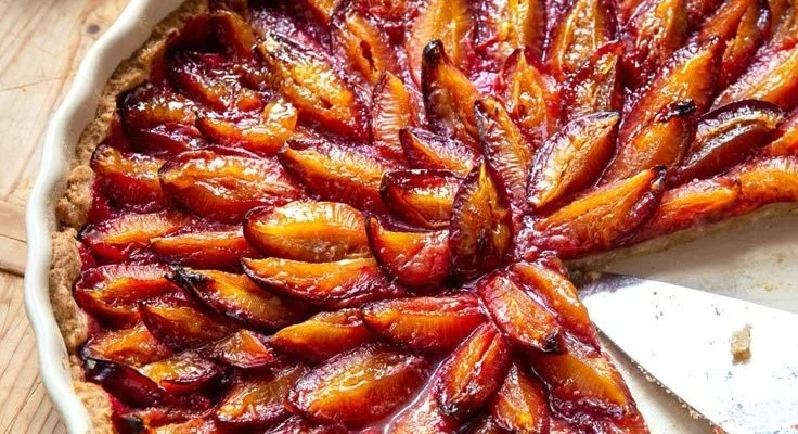 Ein Stück frisch gebackene Zwetschgen-Tarte auf einem Teller.