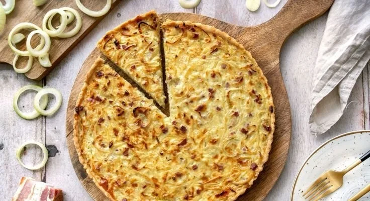 Zwiebelkuchen mit Mürbeteig, frisch gebacken und serviert auf einem Holzbrett